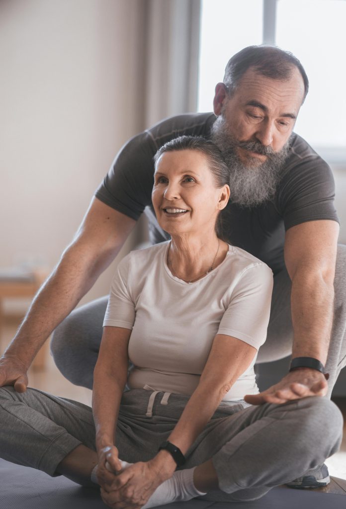 Elderly couple engaging in a yoga session at home, promoting health and happiness.
